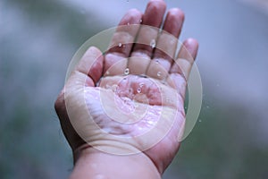 Man`s hand holding rainwater on his hand.