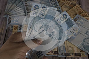 Man\'s hand holding 100 reais banknotes photo