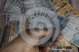 Man's hand holding 100 reais banknotes photo