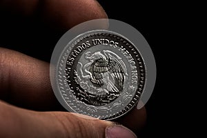 Man's hand holding a silver American coin, close-up of a quarter dollar coin isolated over black. Bag, dollars