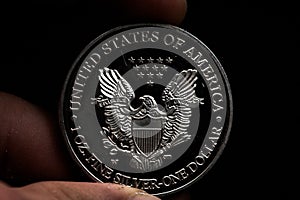 Man's hand holding a silver American coin, close-up of a quarter dollar coin isolated over black. Bag, dollars