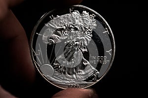 Man's hand holding a silver American coin, close-up of a quarter dollar coin isolated over black. Bag, dollars