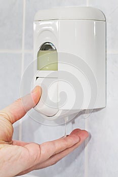 Man's hand holding soap from the soap dispenser