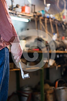 Man`s hand holding a socket metal wrench with ratchet in the gar