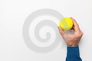 Man& x27;s hand holding a tennis ball on a white background, space for advertising