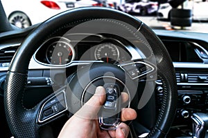 Man`s hand holding a wireless car key in black leather interior. Modern Car interior details. Car detailing. Car inside. Car deta