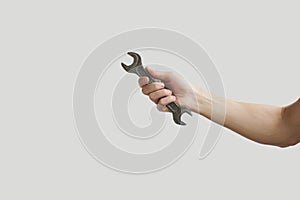 Man's hand holding wrench isolated over grey.