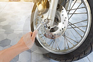 Man's hand is holding a wrench to tighten the nut of the motorcycle's lower disc brake pump