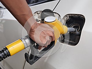 Man's hand holding a yellow fuel dispenser. gas station. fill e20 fuel in car. power and gas