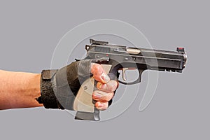 A man& x27;s hand holds a black pistol in his hand on a gray background