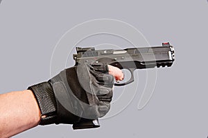 A man& x27;s hand holds a black pistol in his hand on a gray background