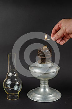 A man`s hand holds a burning match next to the wick of an oil la