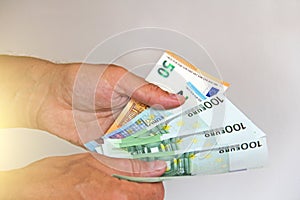 The man`s hand holds the 100 euro, considers them and pays. Pape