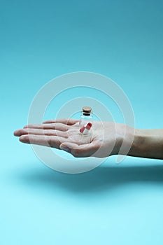Man`s hand holds a glass transparent jar with pills on a light background close-up. medicines and vitamins. pharmaceuticals.