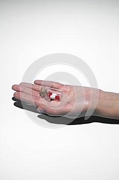 Man`s hand holds a glass transparent jar with pills on a light background close-up. medicines and vitamins. pharmaceuticals.