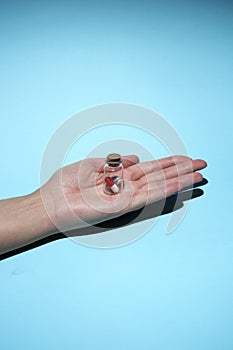 Man`s hand holds a glass transparent jar with pills on a light background close-up. medicines and vitamins. pharmaceuticals.