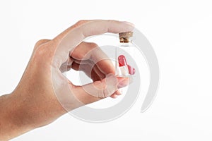 Man`s hand holds a glass transparent jar with pills on a light background close-up. medicines and vitamins. pharmaceuticals