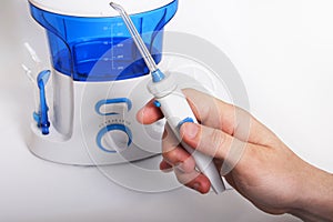 Man`s hand holds the handle of oral irrigator with an individual toothbrush. Side nozzles for tongue, delicate cleansing sensitiv