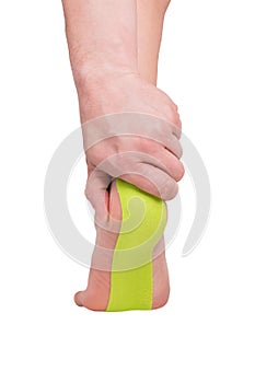 Man`s hand holds the heel, medical tape is glued on the foot to relieve pain, isolated on white