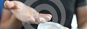 Man`s hand holds jar with a white substance inside.