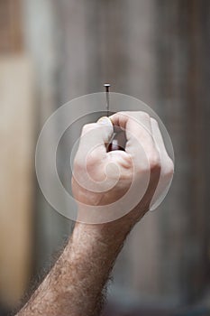 A man`s hand holds one old hobnail. Renovation concept, start of renovation. Close-up