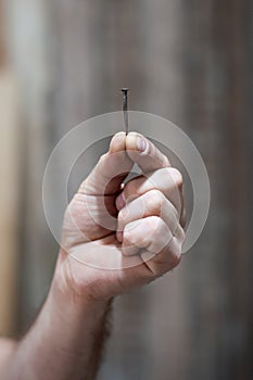 A man`s hand holds one old hobnail. Renovation concept, start of renovation. Close-up