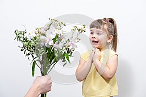A man`s hand holds out a bouquet of white flowers to a cute little girl