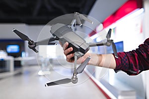 man`s hand holds a quadcopter in the background of a electronics store. Purchase a dron in a hardware store photo