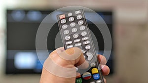 A man`s hand holds the remote from the TV and switches channels. Close-up, moving camera