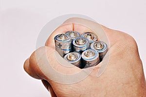 A man`s hand holds several aa batteries. close-up. light background photo