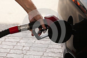 Man& x27;s hand is inserting a gas pump nozzle in a fuel tank, Car refueling on the petrol station, Oil and gas concept