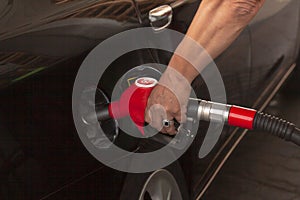Man's hand is inserting a gas pump nozzle in a fuel tank, Car refueling on the petrol station, Oil and gas concept