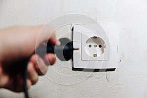 The man`s hand inserts the plug from the socket