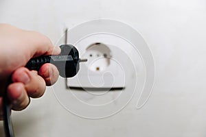 The man`s hand inserts the plug from the socket