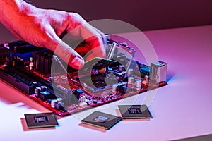 A man`s hand inserts a processor into the motherboard chipset