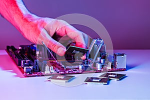 A man`s hand inserts a processor into the motherboard chipset