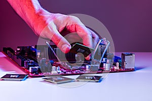 A man`s hand inserts a processor into the motherboard chipset