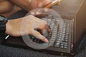 Man`s hand are keying information from Smartphone into laptop. Identity verification code