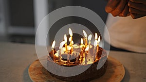 Man's hand lighting candles on birhday cake in a dusk, close up