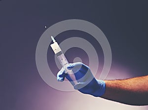 Man`s hand in medical glove holds a syringe