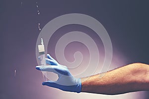 Man`s hand in medical glove holds a syringe