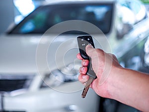 Man`s hand open the car with car remote key at car park