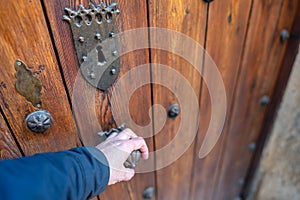 Man& x27;s hand opening a medieval wooden door in the old town of Pedraza, Segovia, Spain.