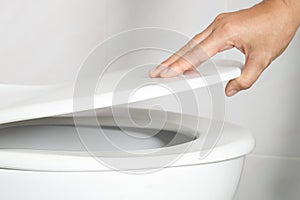 Man`s hand opening the toilet lid