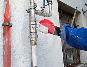 Man`s hand opens or closes gas valve on stainles gas pipe