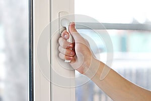 A man`s hand opens a white plastic window. Close up