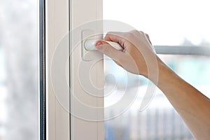 A man`s hand opens a white plastic window. Close up