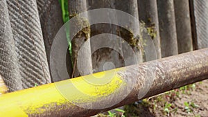 A man's hand paints a rusty pipe with a brush with yellow paint neatly.