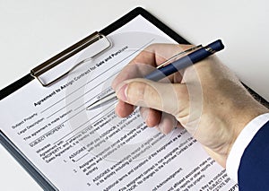 A man's hand with a pen signs a contract in a folder