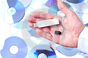 Man's hand with pendrive over CD's background. photo